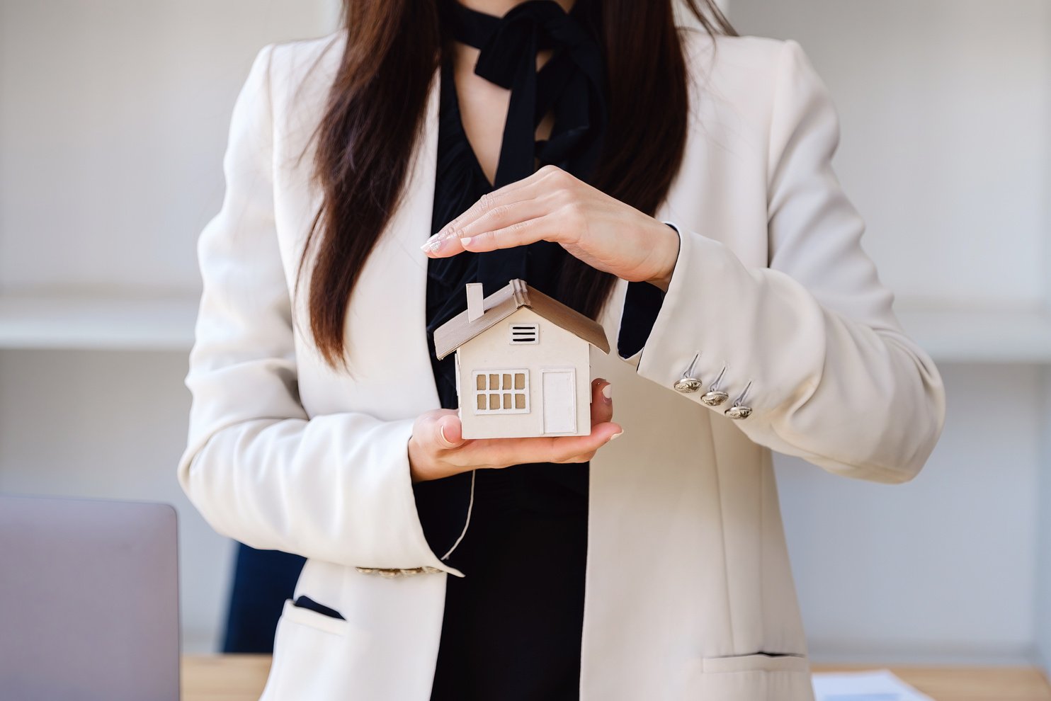 a person in a business suit holding a house model